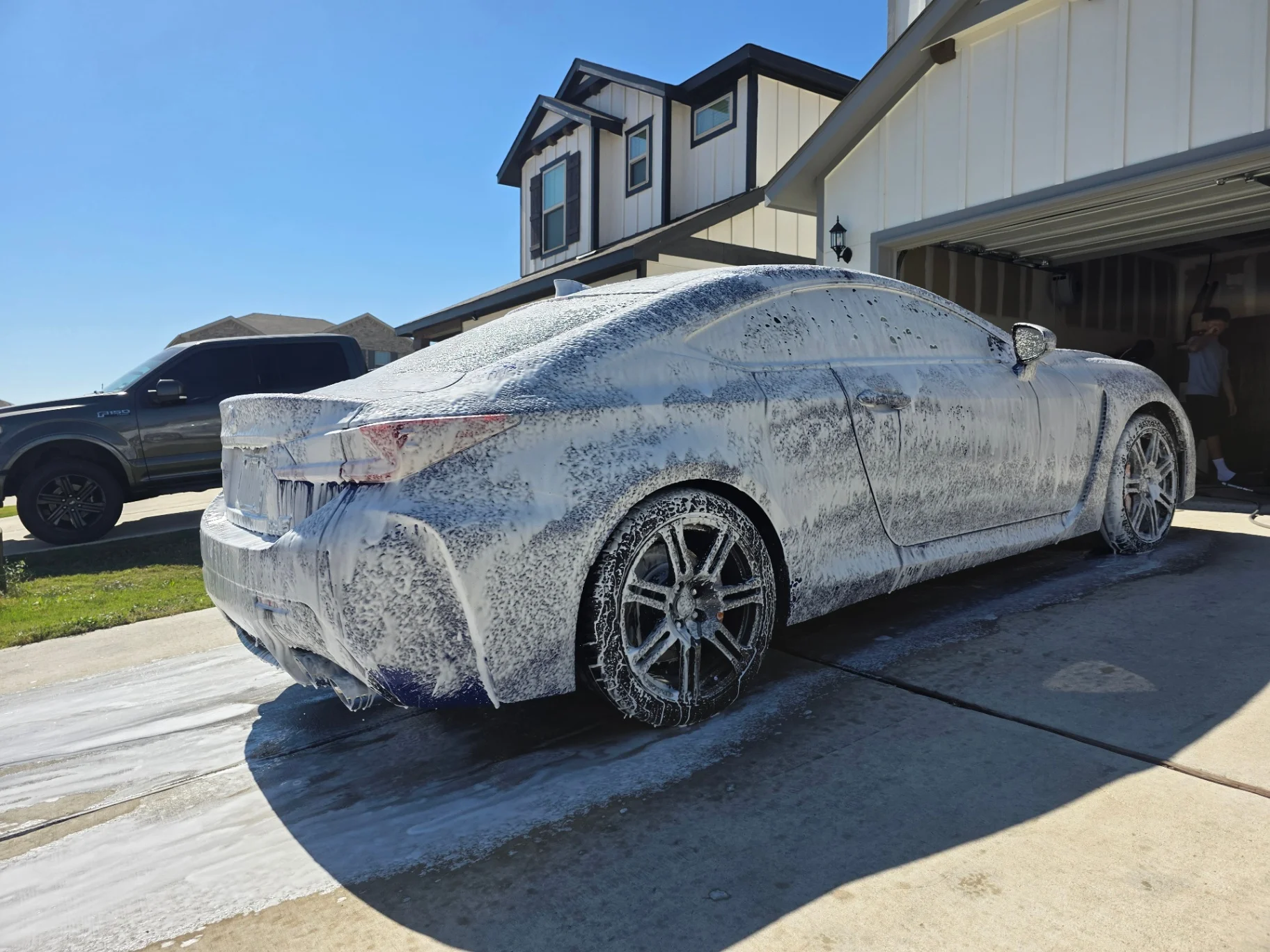 Foam-coated Lexus coupe being washed in the driveway