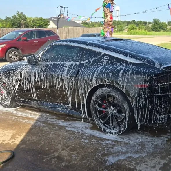 Black sports car covered in thick foam during exterior wash