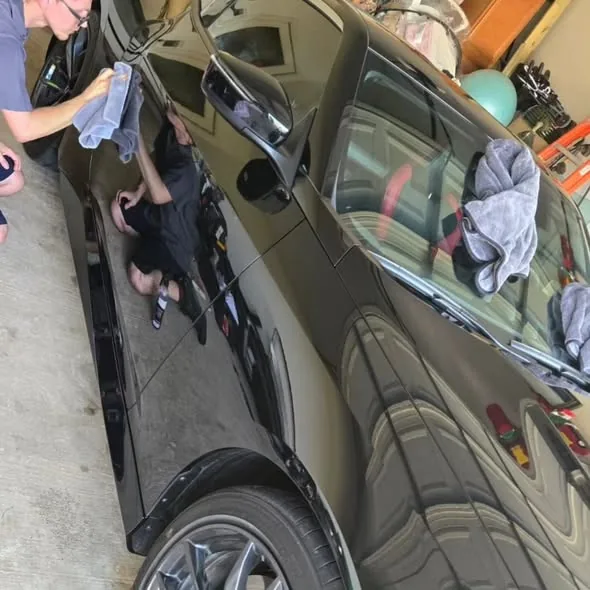 Hand polishing a black sedan to a flawless mirror finish
