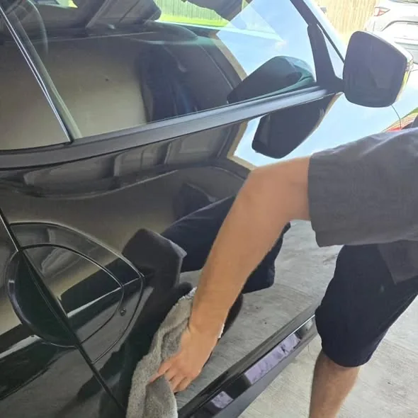 Drying a freshly washed black coupe with a microfiber towel