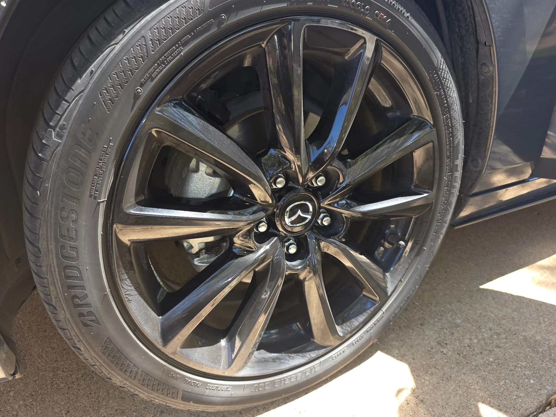 Close-up of a glossy black Mazda wheel after a full wheel detail